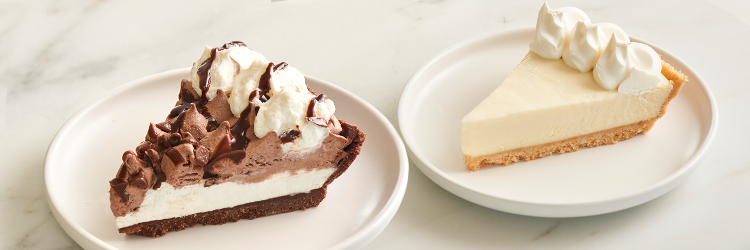 Two dessert slices on white plates: one chocolate and cream pie with whipped topping, and one plain cheesecake with whipped cream.