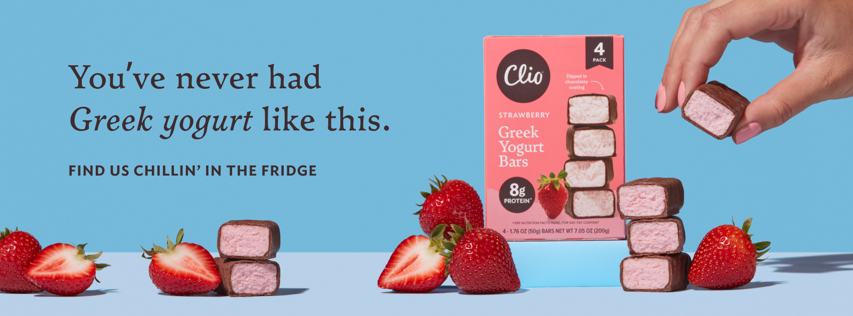 Box of Clio Greek Yogurt Bars with strawberry flavor, surrounded by fresh strawberries and individual bars, on a blue surface.