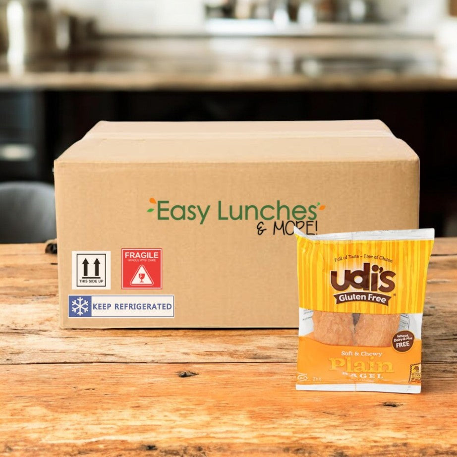 A cardboard box labeled "Easy Lunches & More!" sits on a wooden table next to Udi's Plain Bagel, 3.5 oz. - 1 Case, 24 Pack by Udi's—the perfect gluten-free bagel for a classic lunch option.