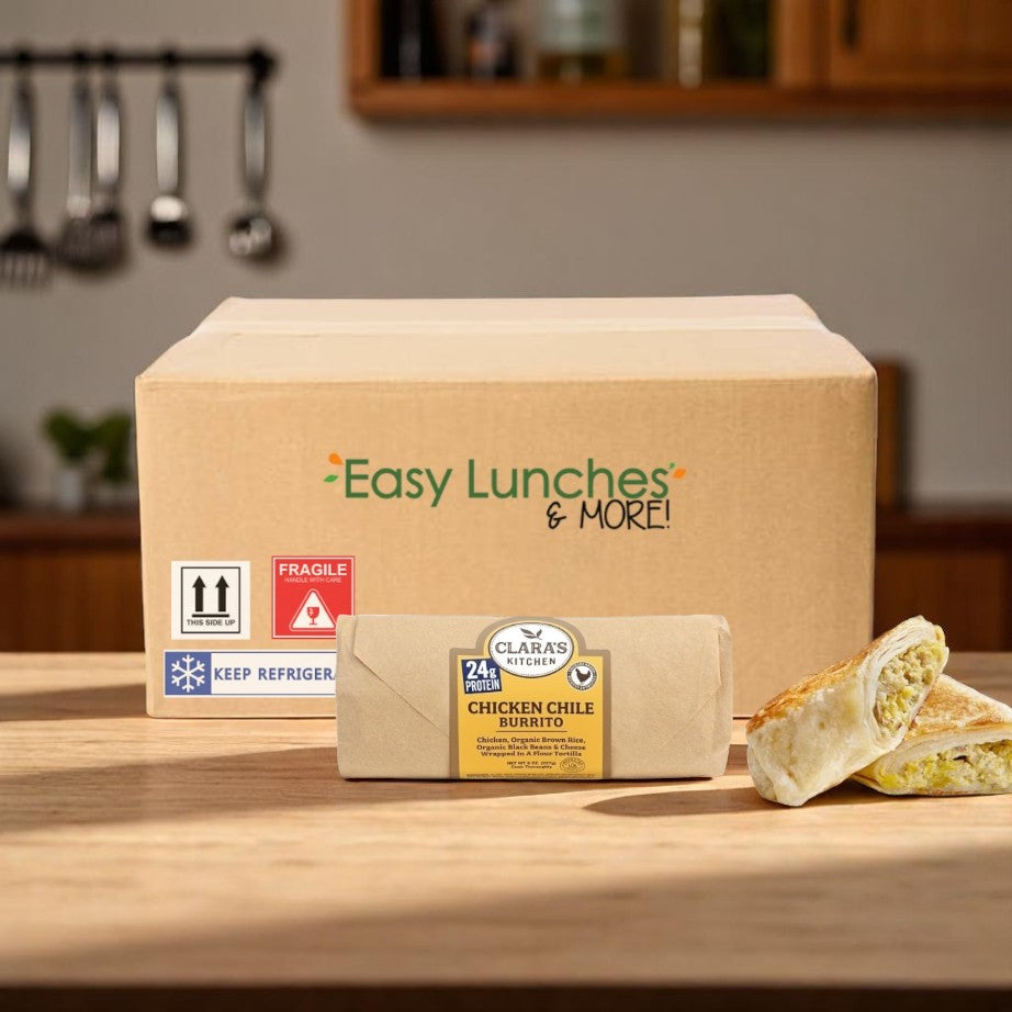 In the kitchen sits a cardboard box labeled "Easy Lunches & More," featuring a Clara's Kitchen individually packaged chicken chile burrito, half-unwrapped and ready-to-eat—the perfect on-the-go meal.