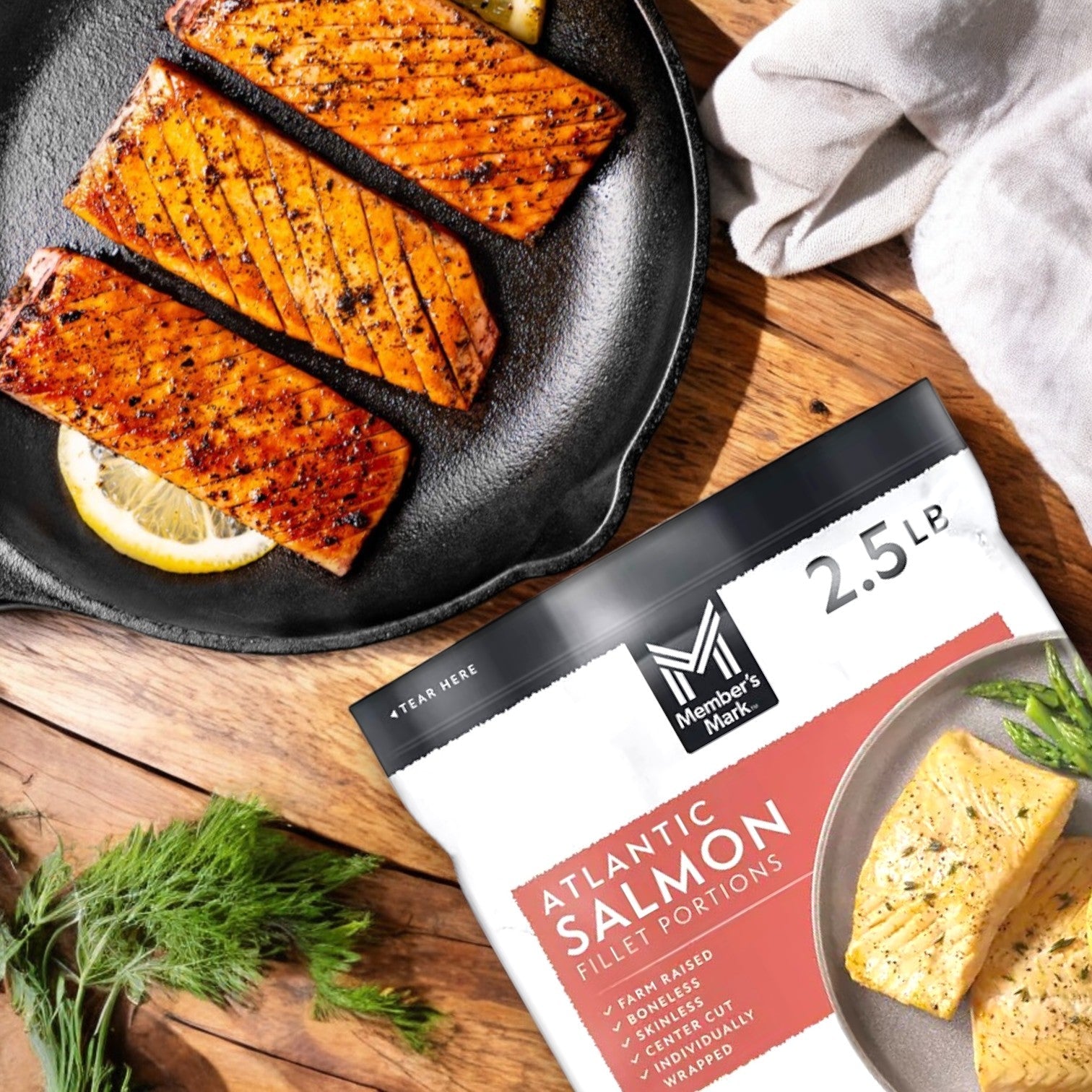 Grilled Member's Mark Atlantic salmon fillets with lemon slices highlight rich Omega-3s, next to a 40 oz. bag of Salmon Filet Portions. Fresh dill and cloth accentuate their sustainable origins.