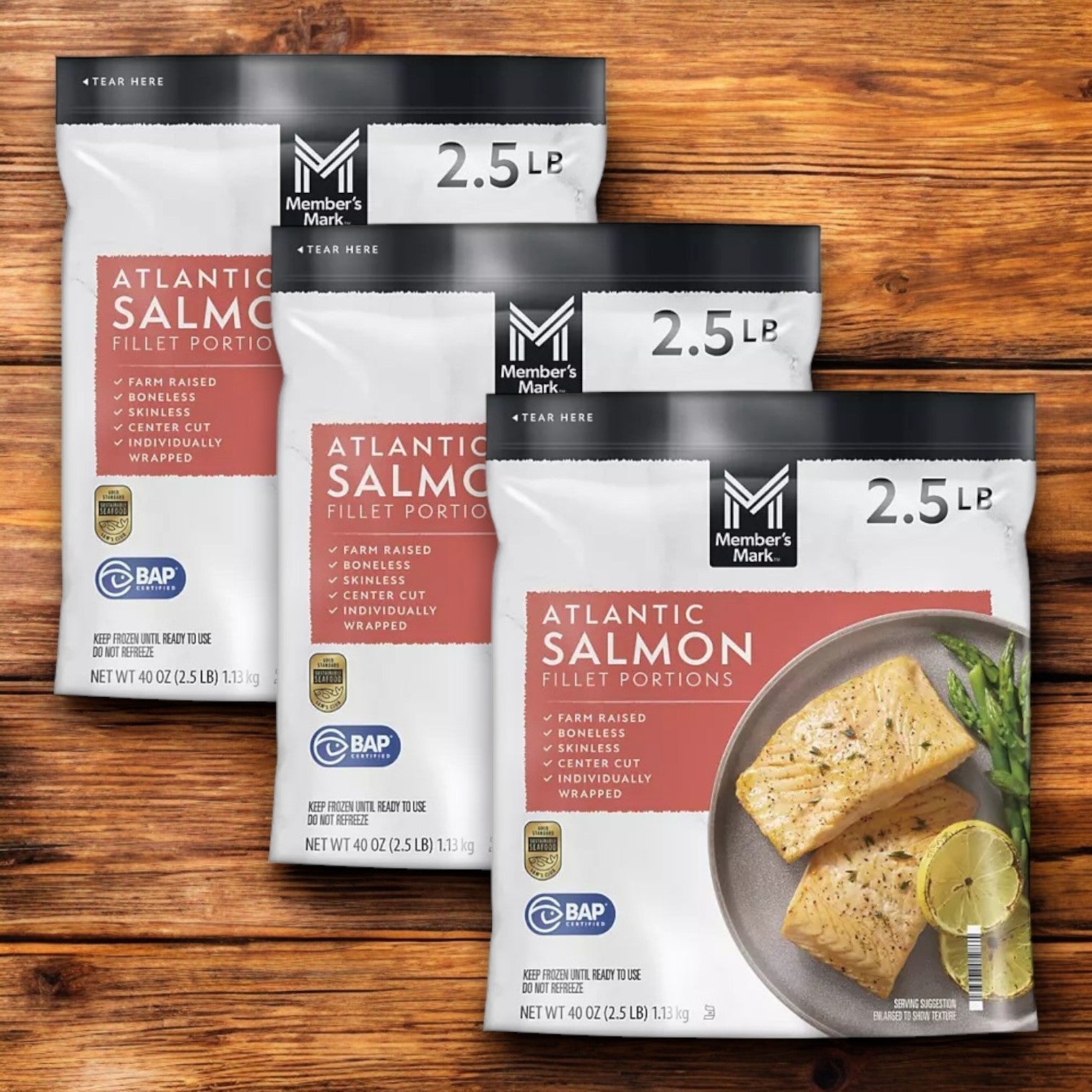 Three 2.5 lb packs of Member's Mark Atlantic Salmon Fillet Portions, rich in omega-3 fatty acids, are placed on a wooden surface.