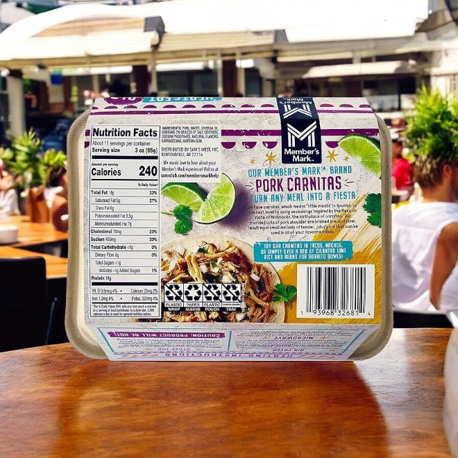 A box of Member's Mark Fully Cooked Pork Carnitas, highlighting its savory slow-cooked flavor and nutrition details, is elegantly displayed with a serving suggestion on a wooden table outside. As it comes fully cooked and ready to serve, it's an ideal option for an enjoyable meal in the fresh air.