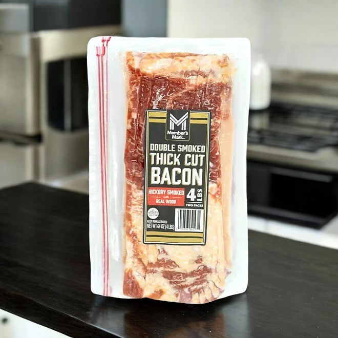 A package of Member's Mark Double Smoked Thick Cut Bacon, 2 lbs, 2 pk, 1 Case, hickory smoked with real wood, is displayed on a kitchen counter.