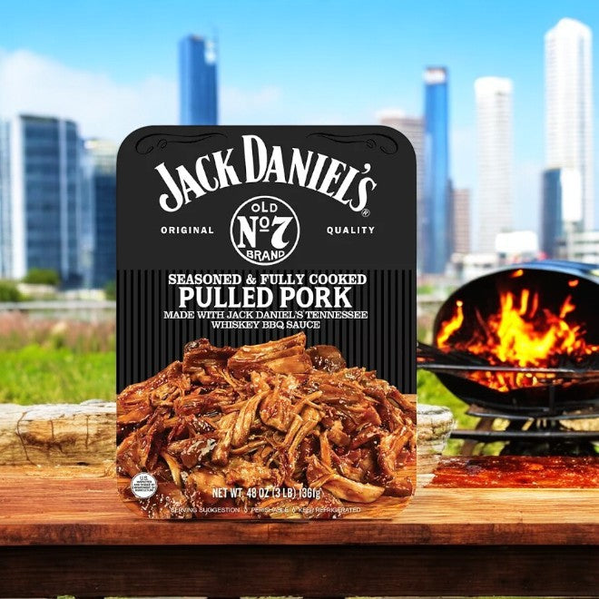 Jack Daniels Pulled Pork, 3 lbs-1 Count, features packaging adorned with a city skyline and a grill backdrop, encapsulating the smoky sweetness of Tennessee Whiskey in every bite.