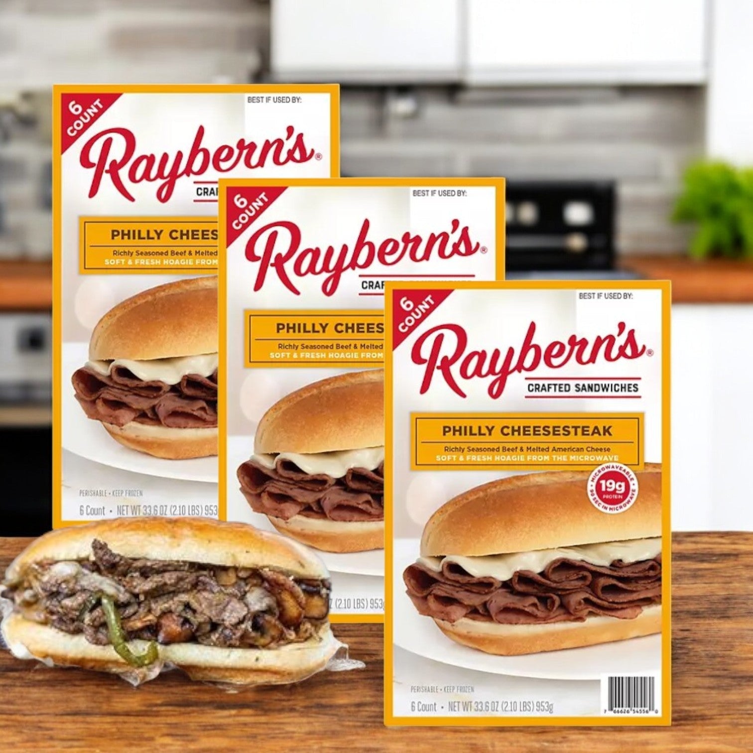 Boxes of Raybern's Philly Cheesesteak Crafted Sandwiches (3 Packs, Frozen, 6 count each) are displayed with an unwrapped, protein-rich sandwich in front.