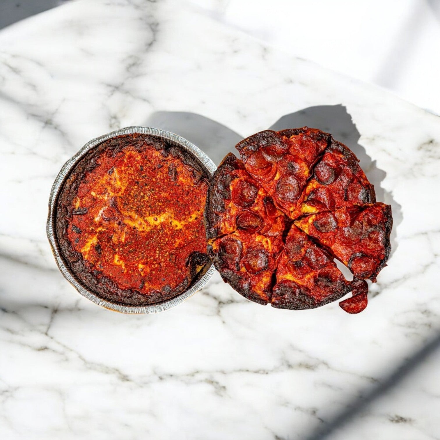 The Pequod Pizza Deep Dish 2-Pack Combo features two Chicago pizzas on a marble surface: one with caramelized crust and the other topped with pepperoni slices.