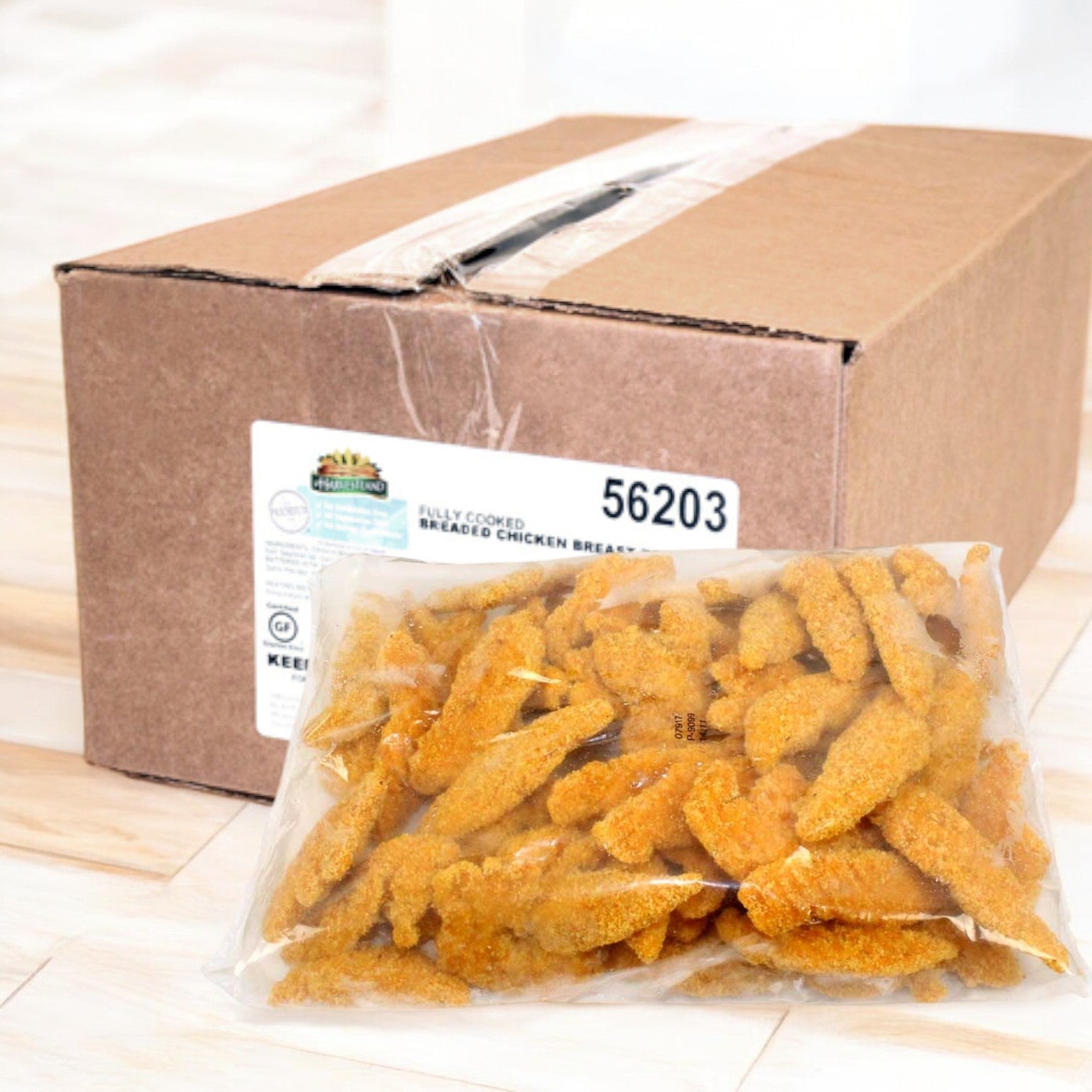 A bag of Perdue's Harvestland Gluten Free Fully Cooked Breaded Chicken Breast Tenders, 5 lbs., rests invitingly on a light wooden floor in front of a sealed brown box with a label.