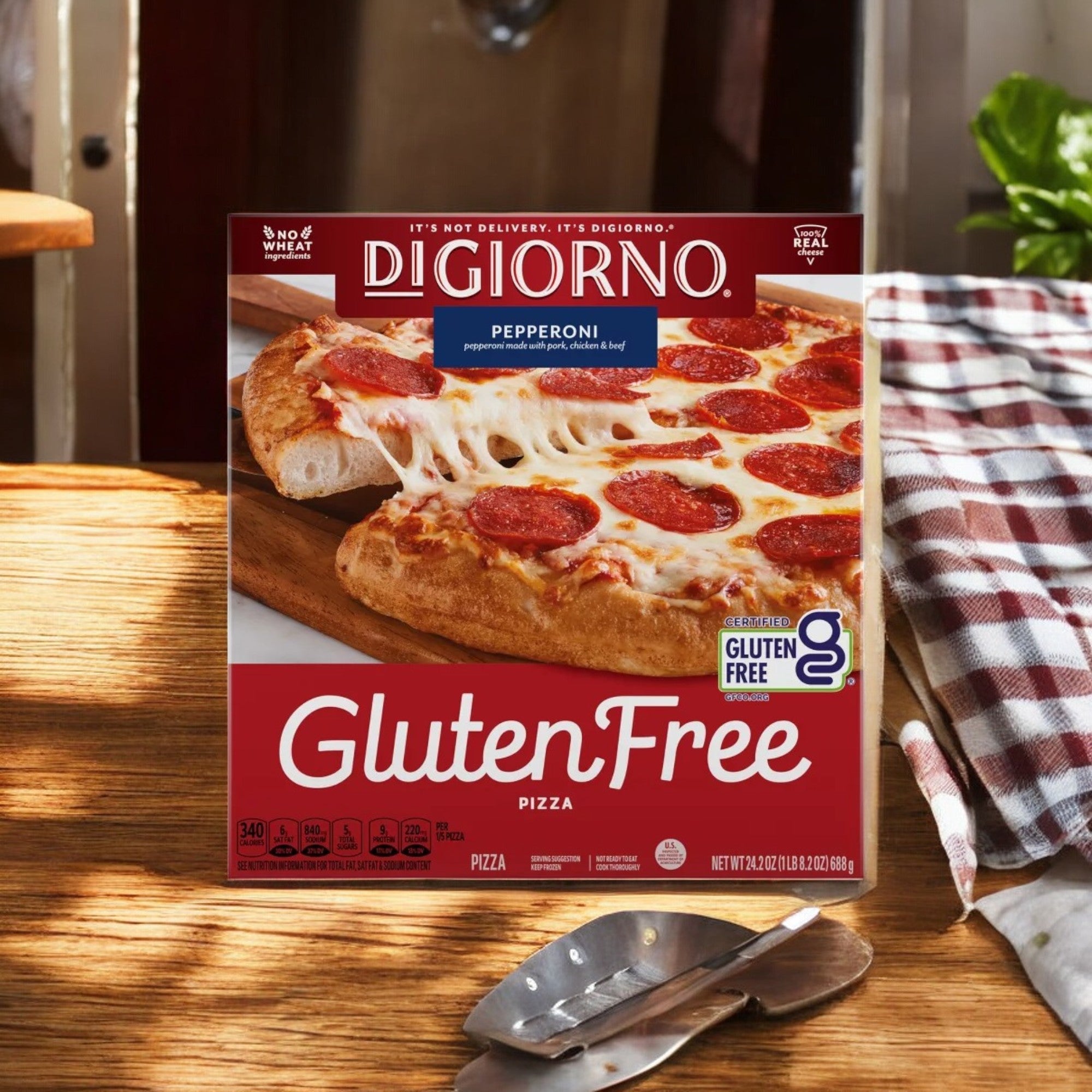 A box of DiGiorno Gluten Free Frozen Pizza- 24.2 Oz-1 Count sits on a wooden table, accompanied by utensils and a checkered cloth. Enjoy the rich taste of gluten-free crust that offers flavor without compromise.