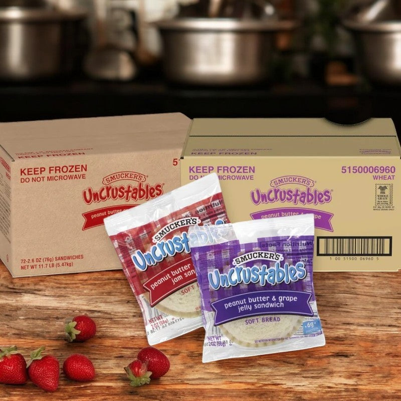 Uncrustable Smuckers' Uncrustables 144 count (72 Grape, 72 Strawberry) are hassle-free snacks, beautifully displayed on a wooden surface with fresh strawberries in the background. Ideal for anyone craving delicious and convenient ready-to-eat treats!.