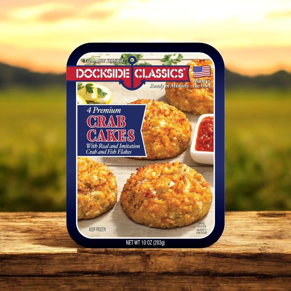 The Dockside Classics Gourmet Crab Cakes package features four delectable cakes made with real and imitation crab and fish flakes, presented on a wooden surface with a blurred outdoor backdrop for the ultimate seafood experience.