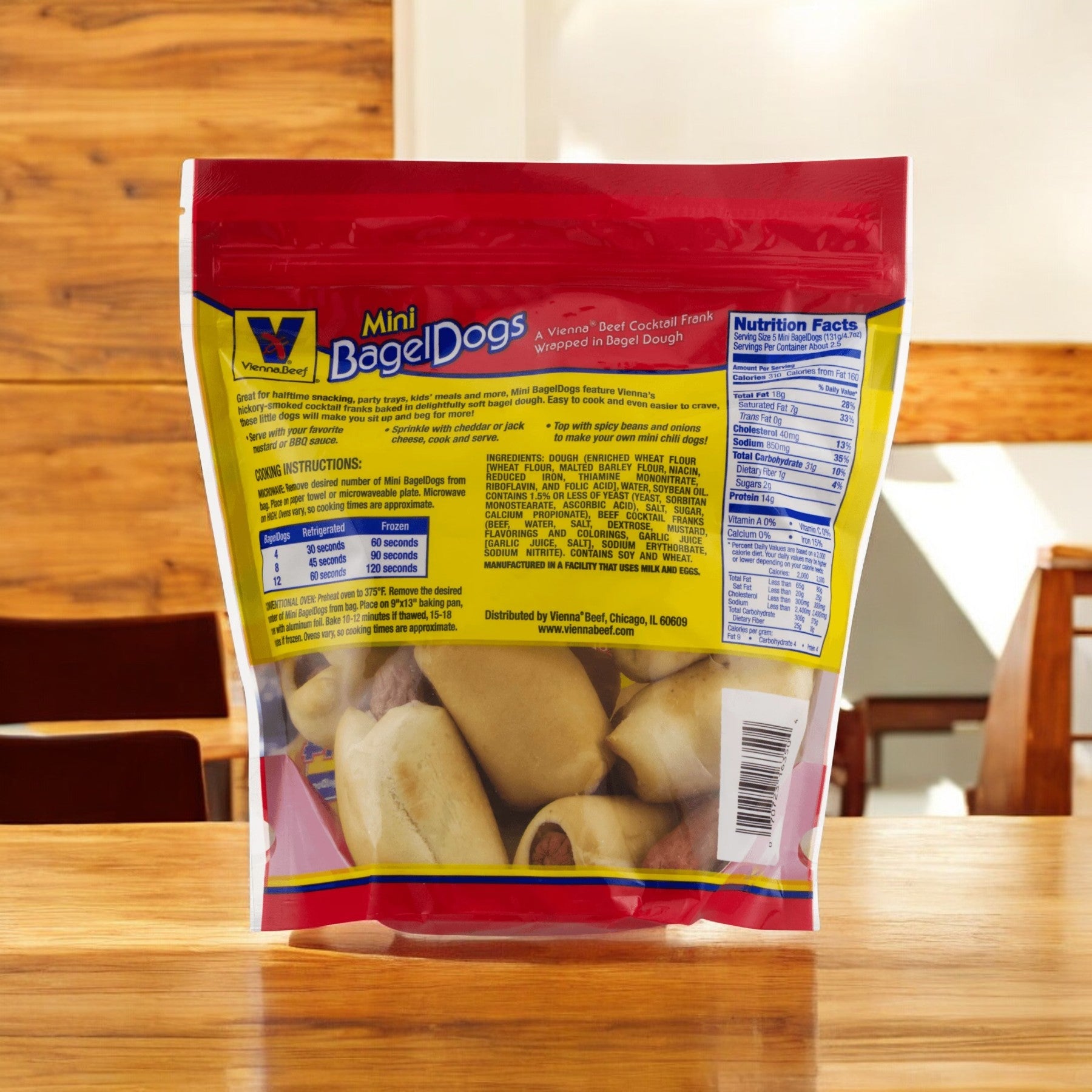 A package of Vienna Beef Natural Mini Bagel Dogs, 12 oz. - 1 Count, is placed on a wooden table, highlighting its natural beef ingredients and premium cocktail franks. The packaging clearly displays nutritional information and cooking instructions.