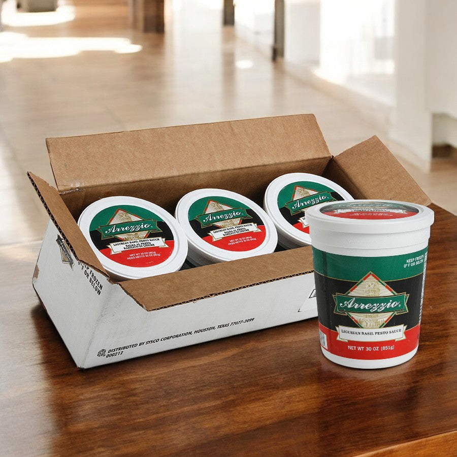A box of Sysco's Arrezzio Imperial Ligurian Basil Pesto Sauce sits on a wooden table, with one 30 oz container outside, highlighting its premium ingredients.