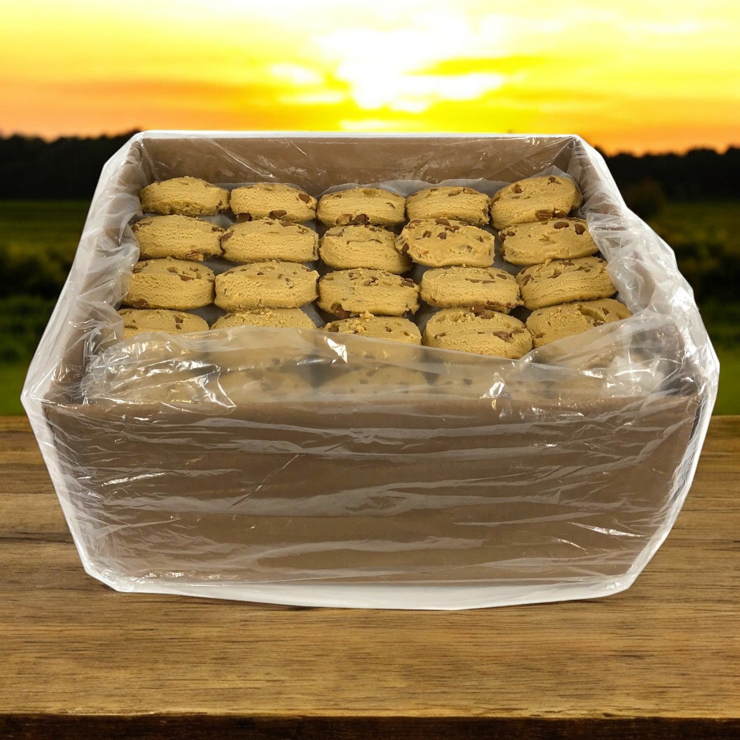 A box of David's Cookies Dough Cookie - Peanut Butter, wrapped in clear plastic, rests on wood under a sunset glow.