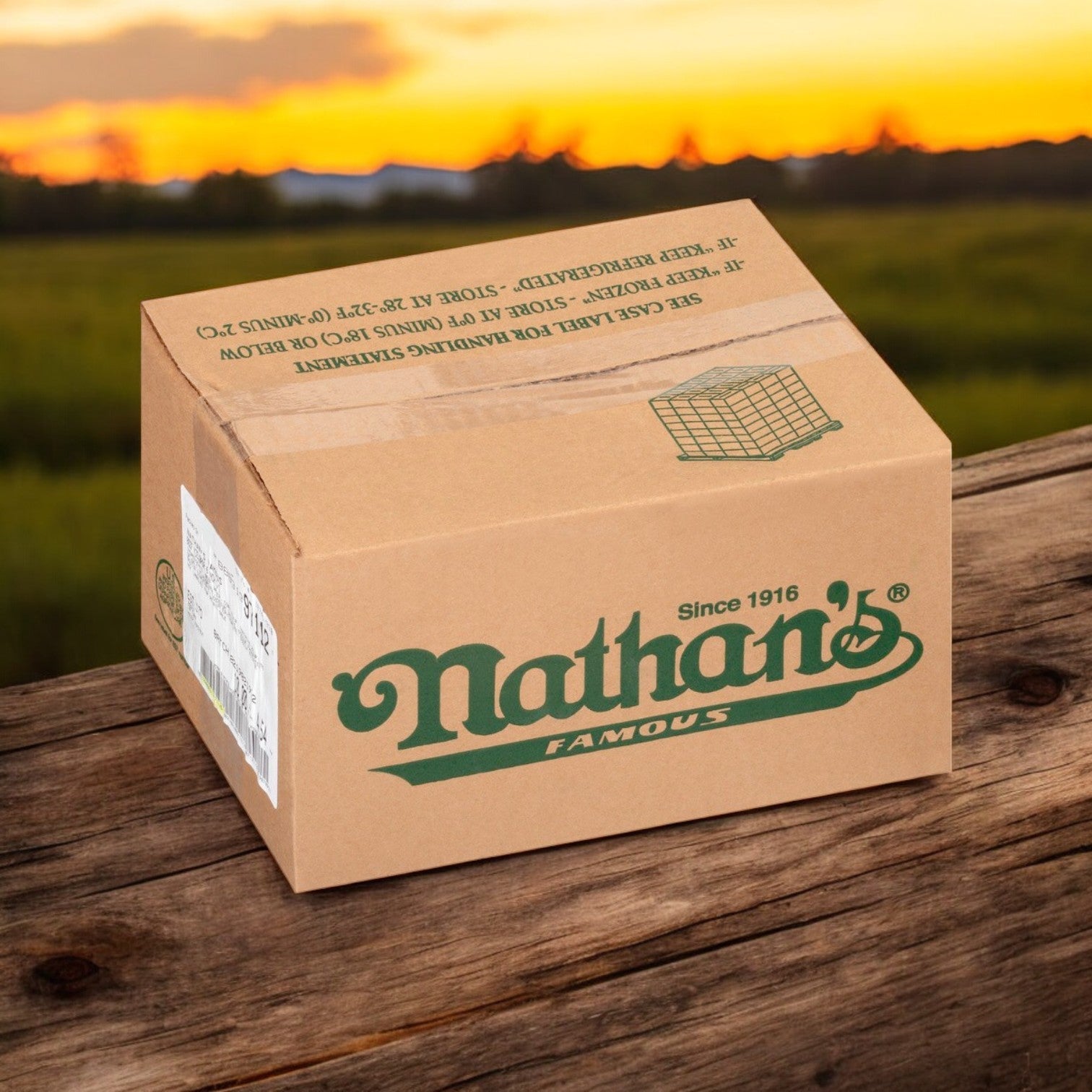 A Nathan's Famous Sausage Polish 10 lbs. case, featuring 50 franks each at six inches, rests on wood against a sunset and grassy field backdrop, epitomizing the timeless allure of Nathan's Famous culinary tradition.