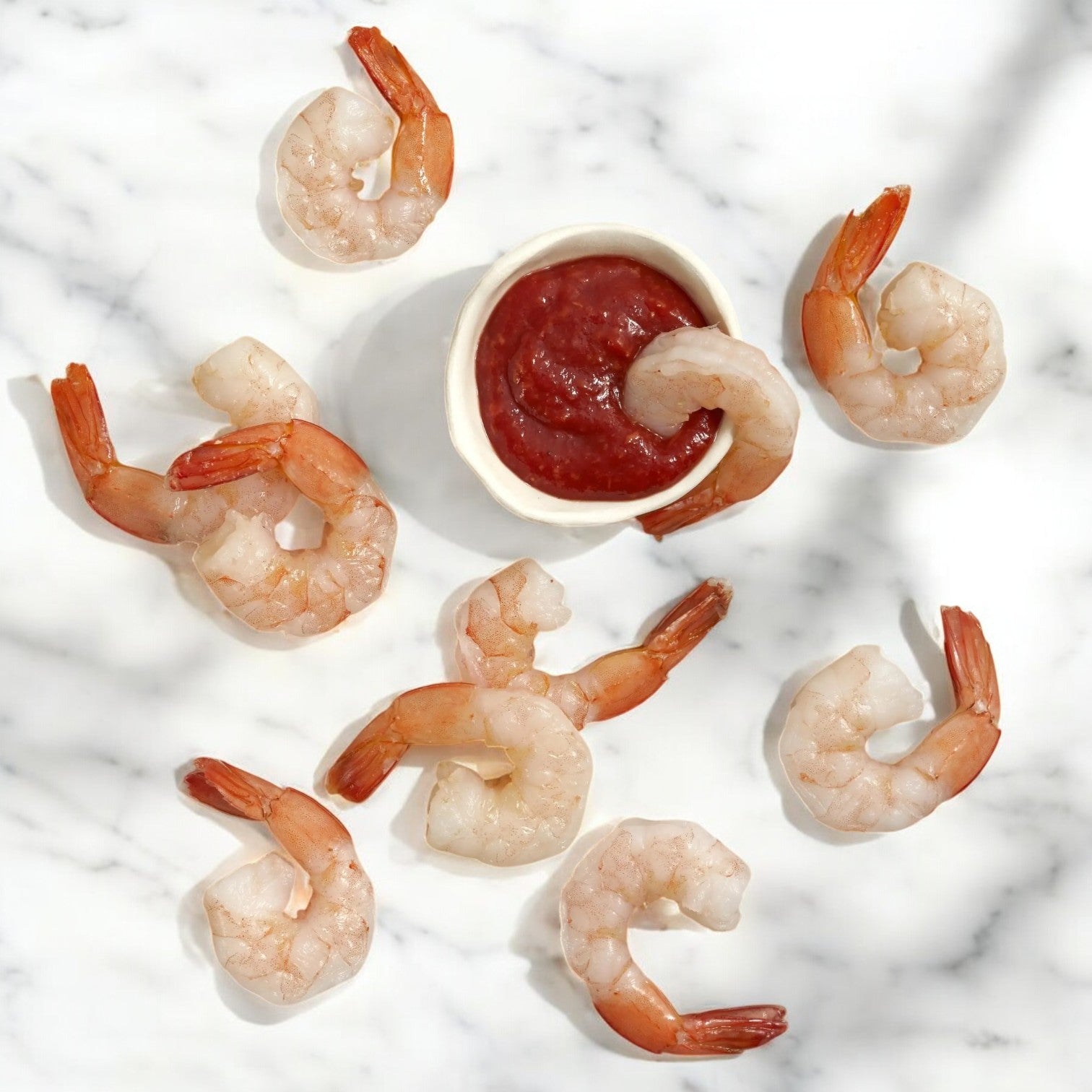 The Sea Mazz Shrimp Platter features eight Seamazz Fully Cooked Cocktail Shrimp beautifully arranged around a bowl of cocktail sauce on a white marble surface.