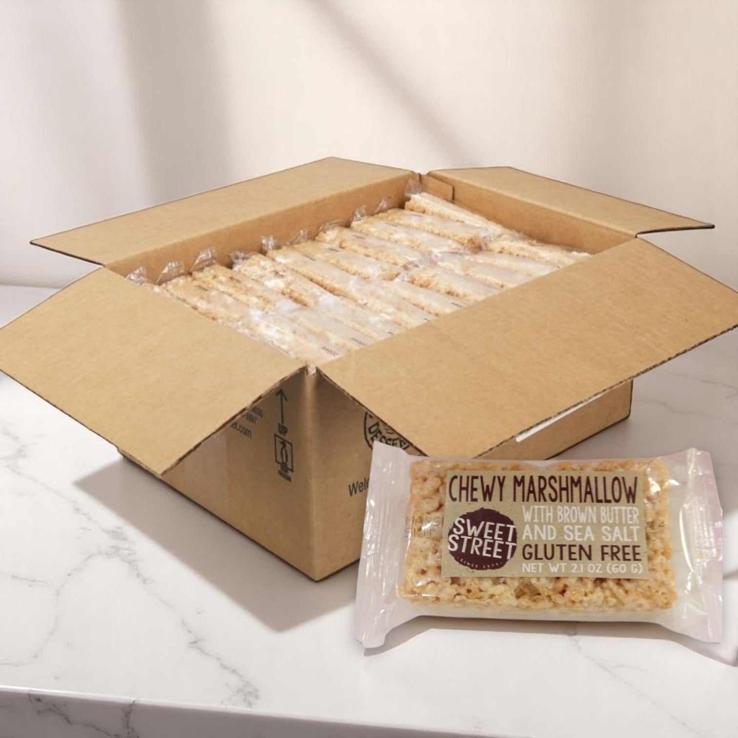An open box of Sweet Street Rice Crispy Snack Bars – Brown Butter & Sea Salt Gluten-Free (40 count, 2.1 oz each) displays individually wrapped bars, with one in front showing the gluten-free label and flavor.