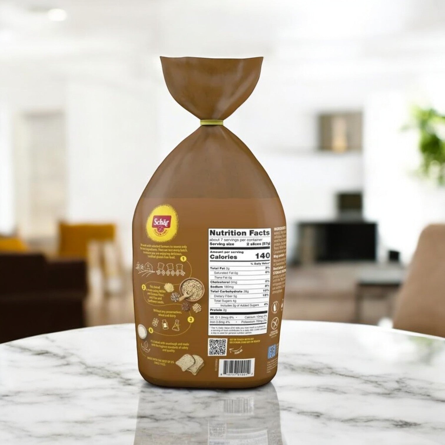 A loaf of Schar Artisan Baker Multigrain Bread sits on a marble table, wrapped in a brown plastic bag and showcasing its nutritional information.
