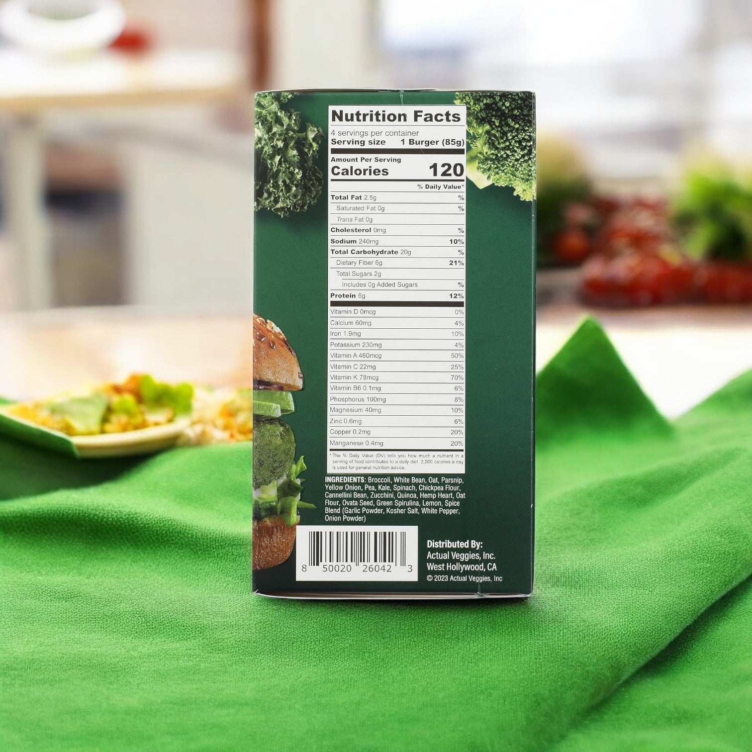 An Actual Veggies Super Greens Veggie Burger, rich in nutrients, rests on a green cloth showing its nutritional facts with a blurred salad backdrop.