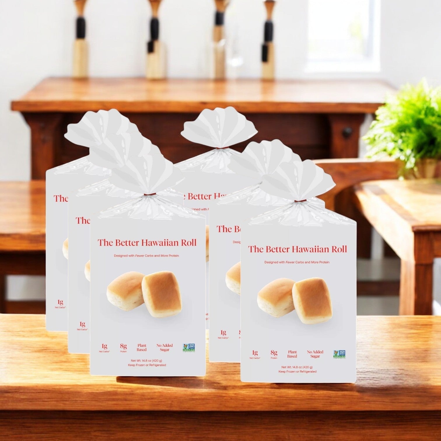 Five packs of BetterBrand's Better Hawaiian Roll, each with 12 rolls, sit on a wooden table against a blurred dining area backdrop.