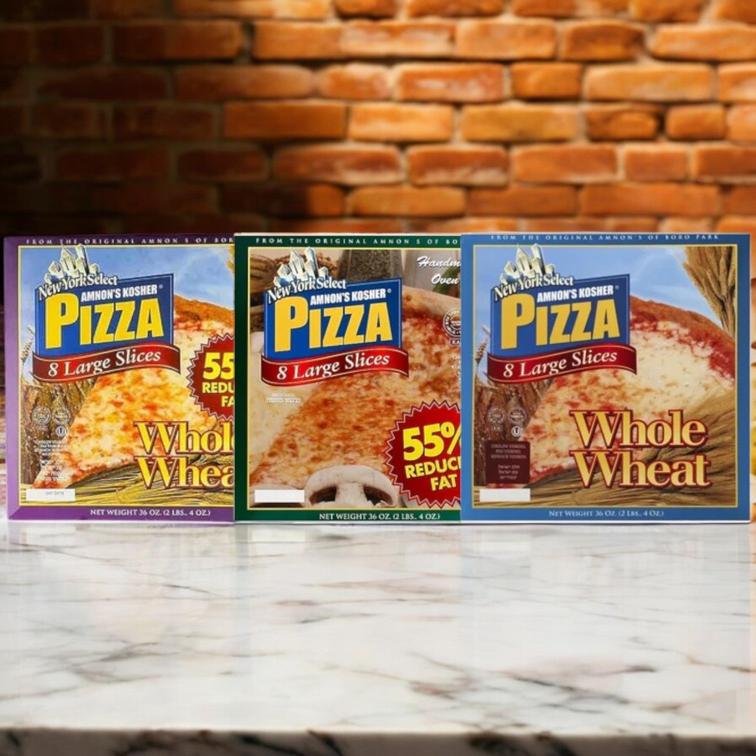 Three boxes of Amnon's Kosher Pizza, a 3-pack bundle, are displayed against a brick wall backdrop. Each ready-to-bake pizza offers a delicious and healthier option with reduced fat content.