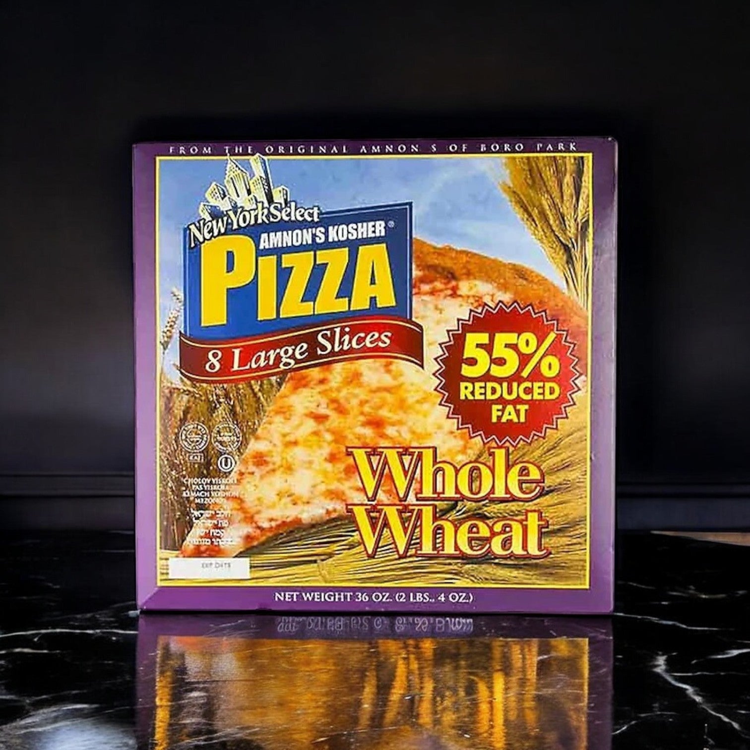 A 36 oz. box of Amnon's Kosher Pizza Whole Wheat Low Fat Frozen, featuring 8 slices with low-fat cheese and 55% reduced fat, elegantly resting on a black marble surface.