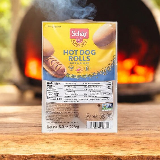 Schar Rolls Hot Dog Gluten Free 4 Count on a wooden surface with a fiery blurred background, ideal for individuals with celiac disease or gluten sensitivities, showcasing nutrition facts and product details.