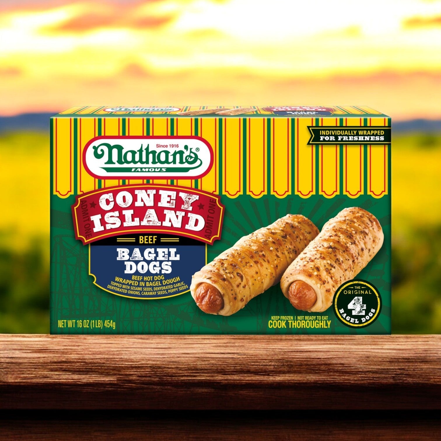 Nathan's Famous, Coney Island Bagel Dogs – 20 oz box is on a wooden surface with a blurred outdoor backdrop, featuring two premium beef hot dogs wrapped in bagels that capture Nathan's iconic taste.