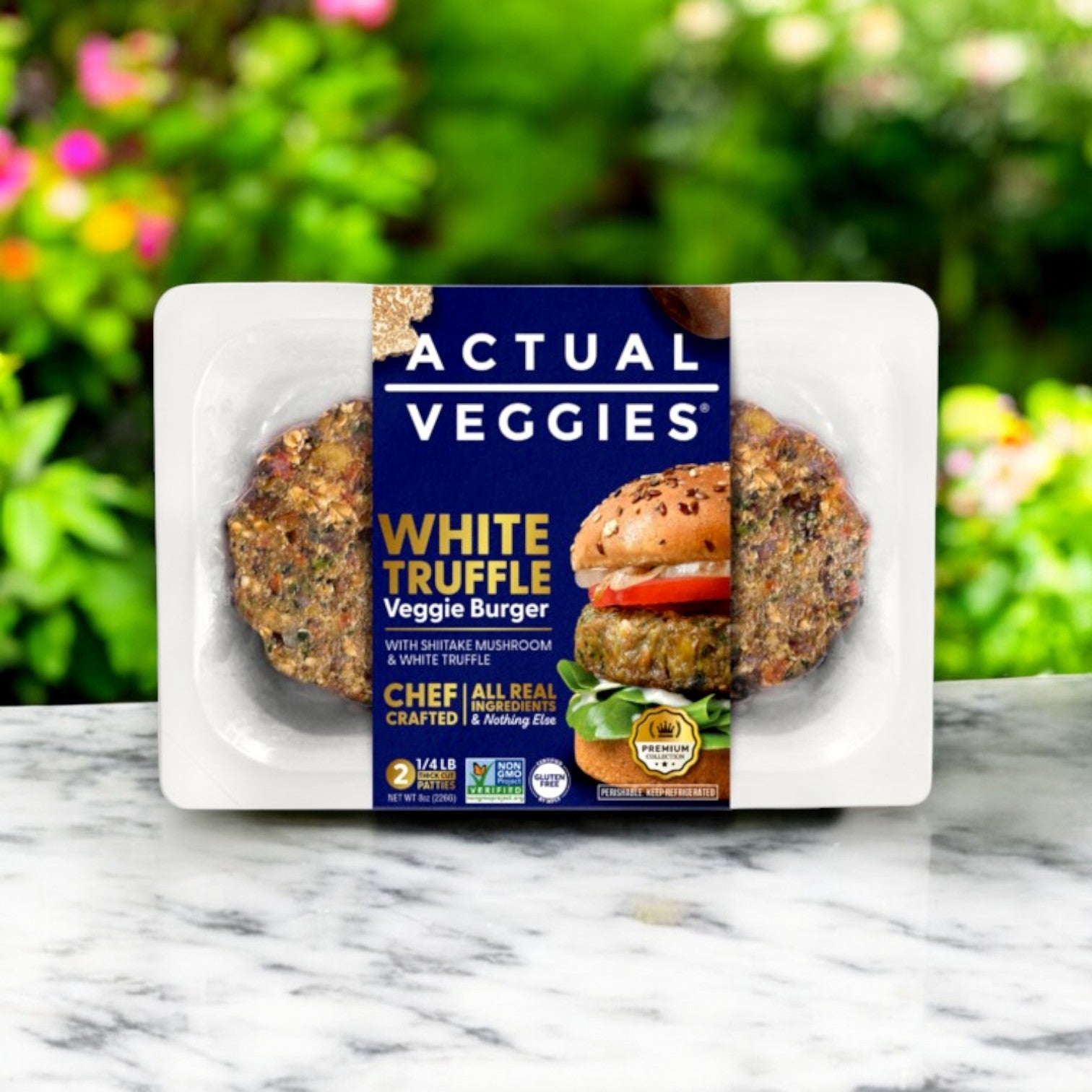 The Actual Veggies White Truffle Veggie Burger – 8 oz package rests elegantly on a marble surface, framed by a blurred garden backdrop.