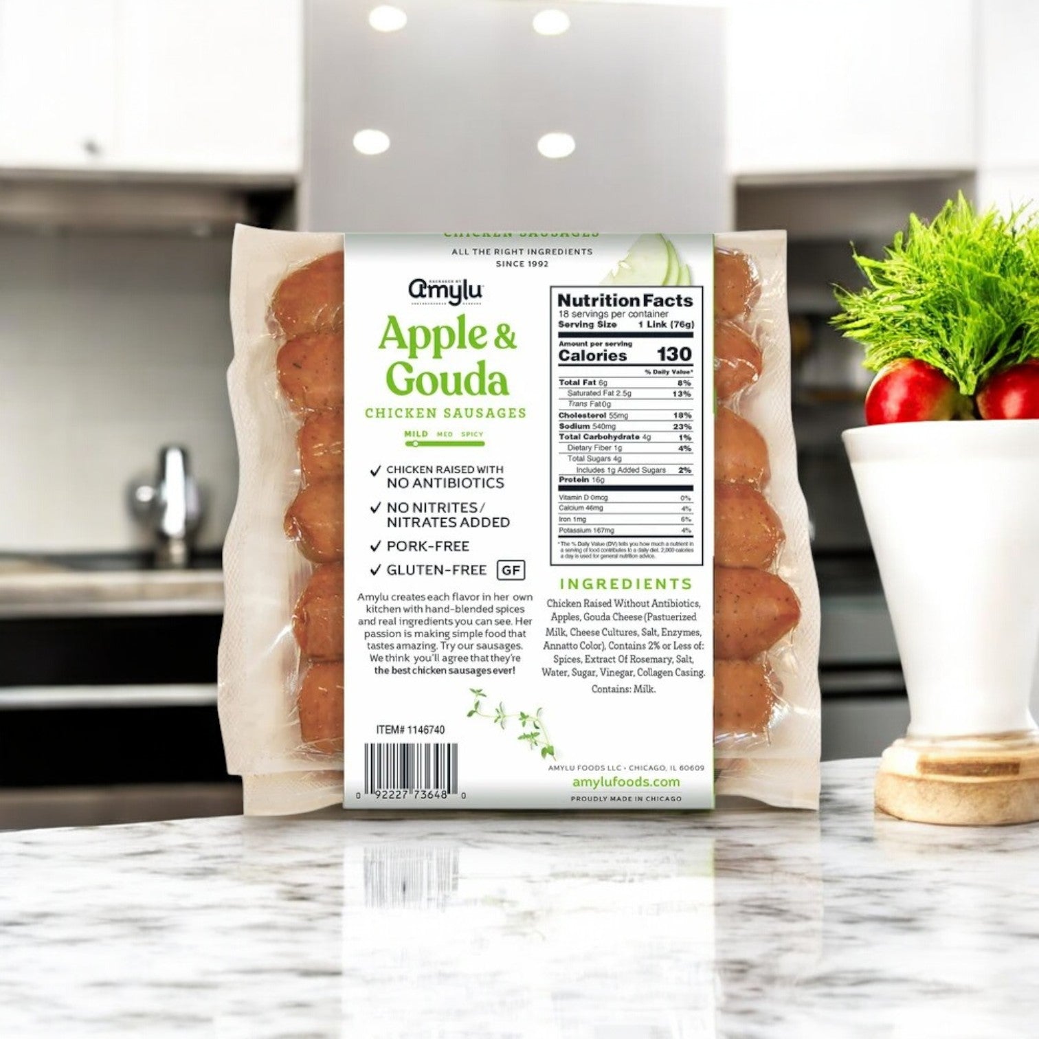 A pack of Amylu Apple & Gouda Cheese Chicken Sausage – 3 lbs (18 ct) sits on the counter, showcasing its premium chicken blend. The label details nutritional facts and ingredients, capturing the gourmet essence.
