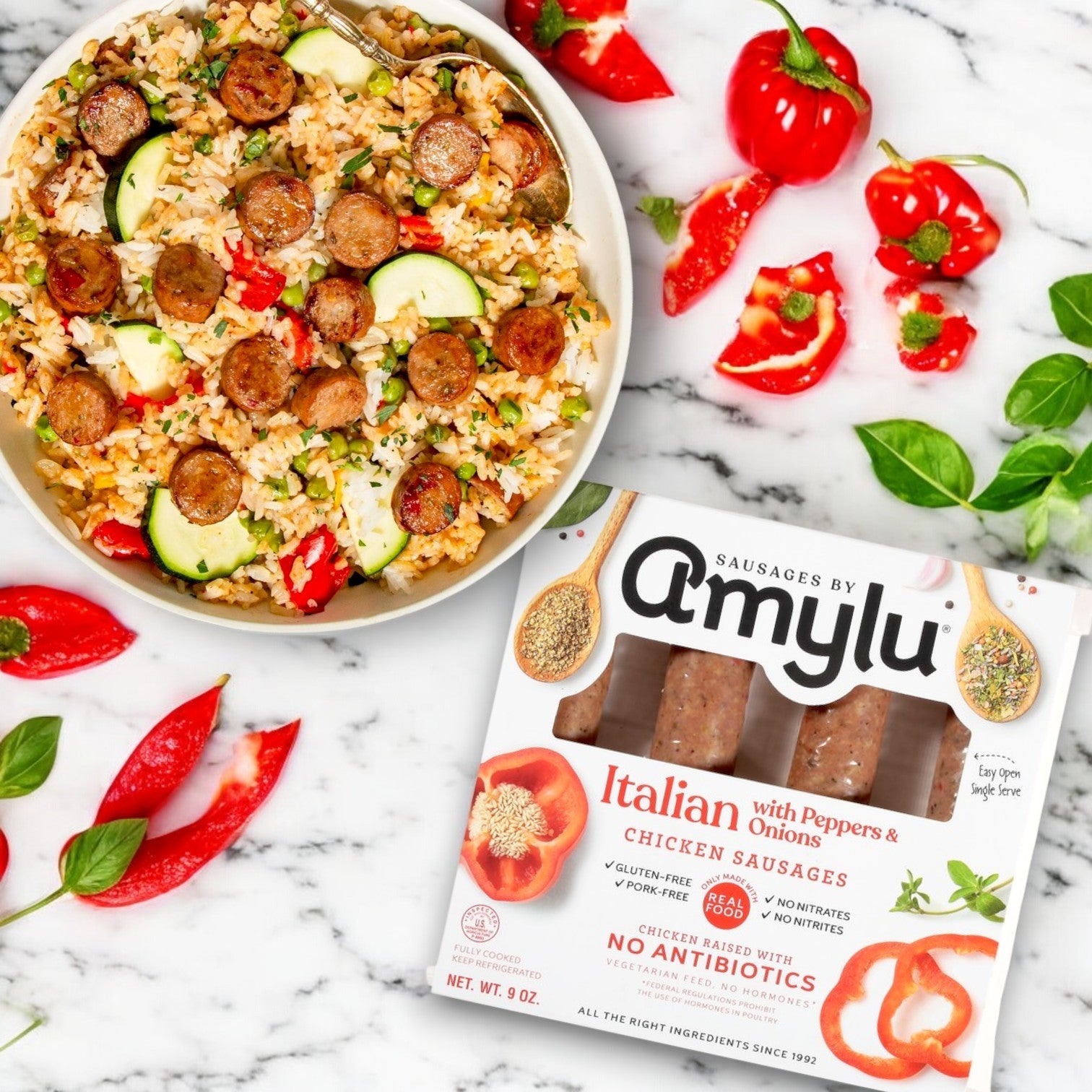 A bowl of rice with zucchini is enhanced by the savory Amylu Italian Chicken Sausage with Peppers & Onions, all displayed alongside a package on a marble surface.