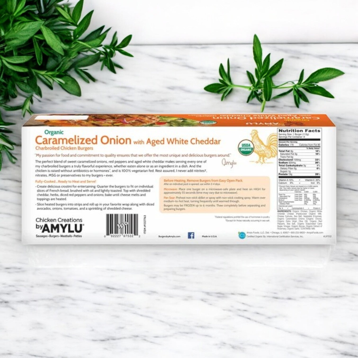 Packaging of Amylu Organic Chicken Burger with Caramelized Onion & Aged White Cheddar – 32 oz, 24-Count, shows nutritional info and herbs in the background.