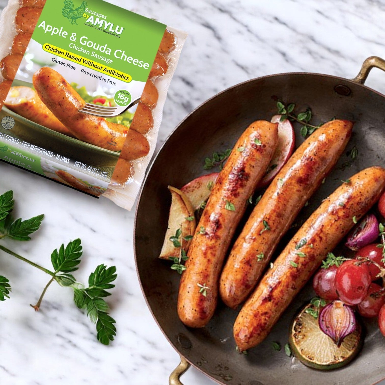 A pan of grilled gourmet sausages rests next to colorful vegetables, with Amylu Apple & Gouda Cheese Chicken Sausage – 3 lbs (18 ct) elegantly placed on the marble surface.