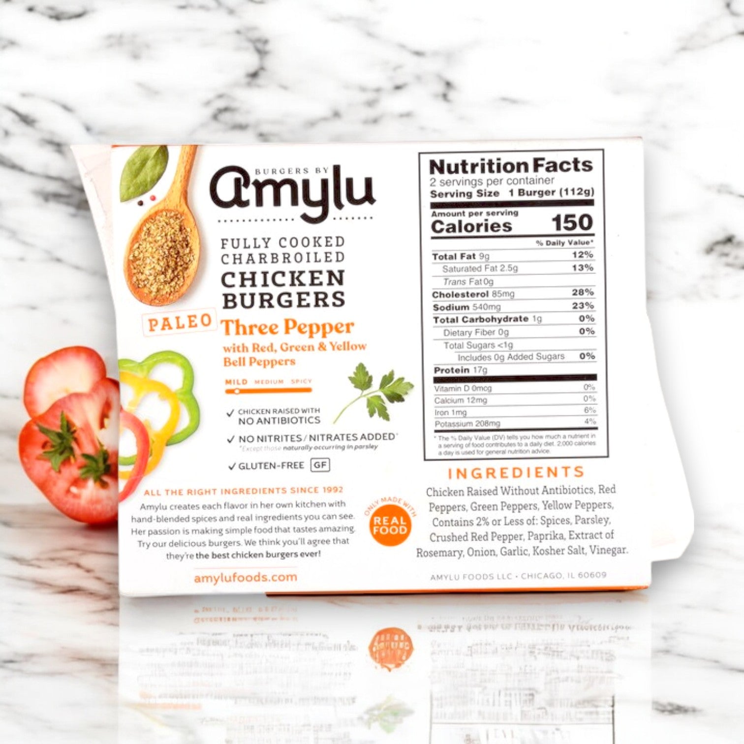 The packaging of Amylu Paleo Three Pepper Chicken Burgers – Charbroiled, 8 oz., showcases they are gluten-free and paleo-friendly, featuring nutrition facts, ingredients list, and a vibrant sliced bell pepper design.