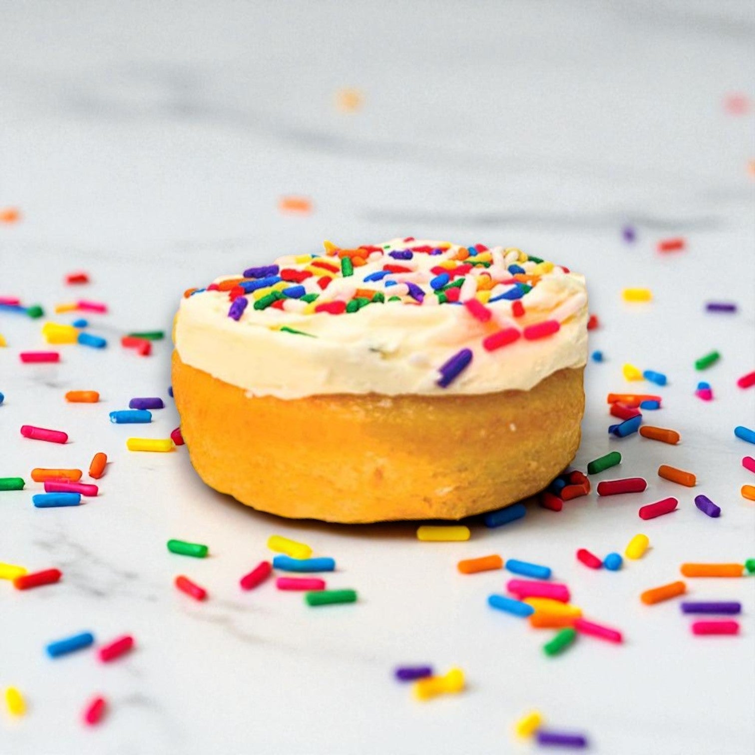 An Eat Cup Cake Birthday Cake Dessert Cup (2.5 oz, spoon included) by Eat Cup Cake sits on a white marble surface, resembling a ready-to-eat treat with extra colorful sprinkles scattered around.