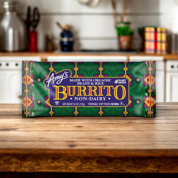 A packaged Amy's Vegan Gluten Free Non-Dairy Bean & Rice Frozen Burrito, 5.5 oz - 1 Burrito, is placed on a wooden surface in a kitchen setting.