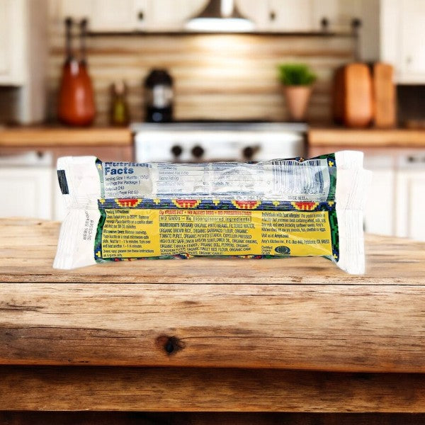 An Amy's Vegan Gluten Free Non-Dairy Bean & Rice Frozen Burrito is placed on a wooden kitchen counter. The back side of the packaging, including nutritional information and details about its organic ingredients, is visible.