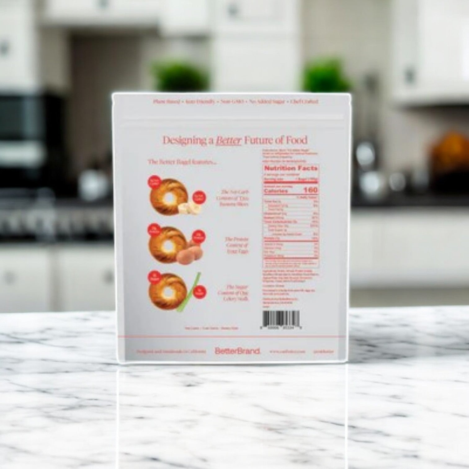 A box of BetterBrand's The Cinnamon Better Bagel (1 Bag, 4 Total Bagels) sits on a marble kitchen counter, highlighting nutrition facts and features these high-protein bagels as a tasty, nutritious option. A blurred kitchen background completes the scene.