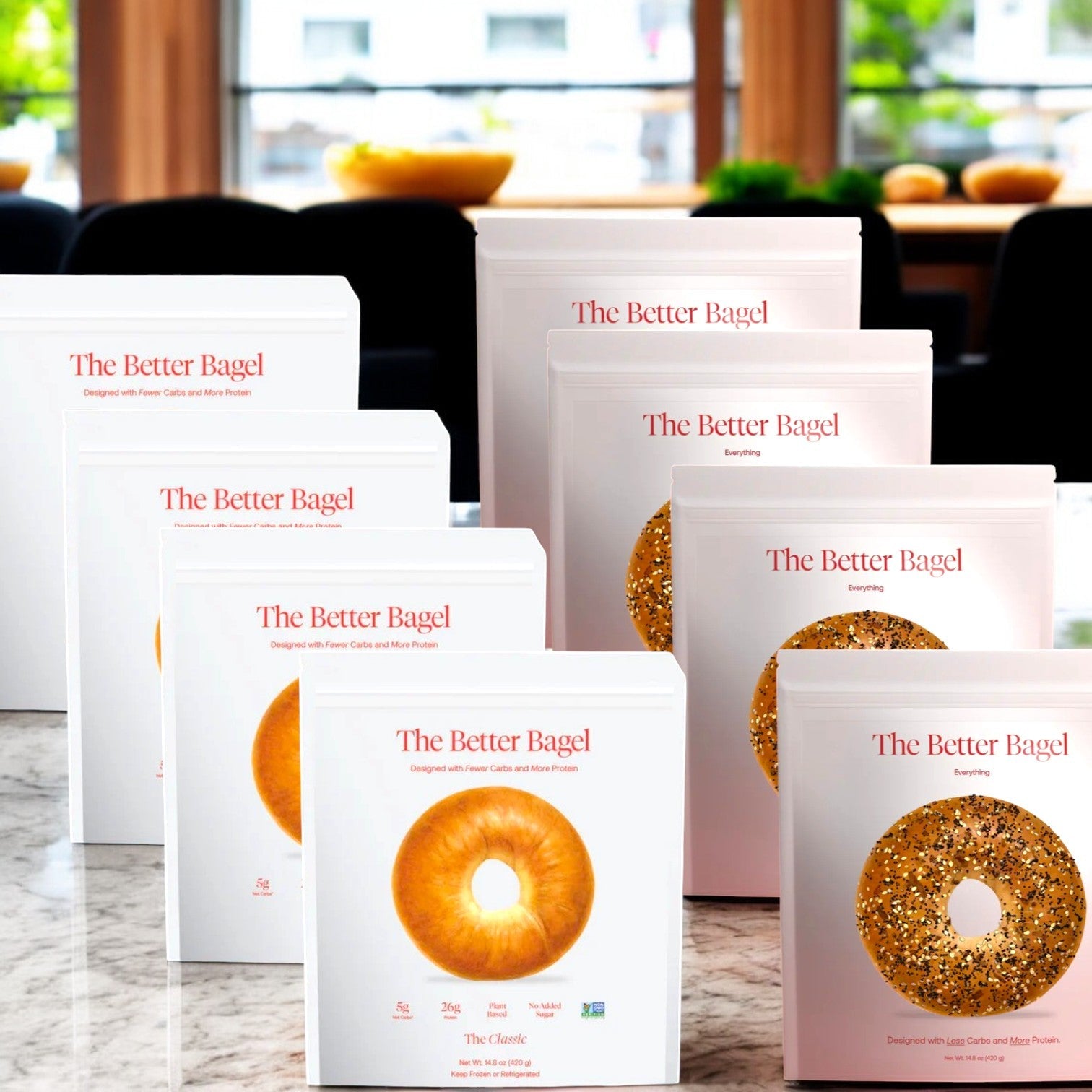 Boxes of BetterBrand's "Better Brand Variety Pack" are displayed on a marble surface. The packaging features images of bagels like "The Everything Bags," highlighting various flavors and nutritional info.