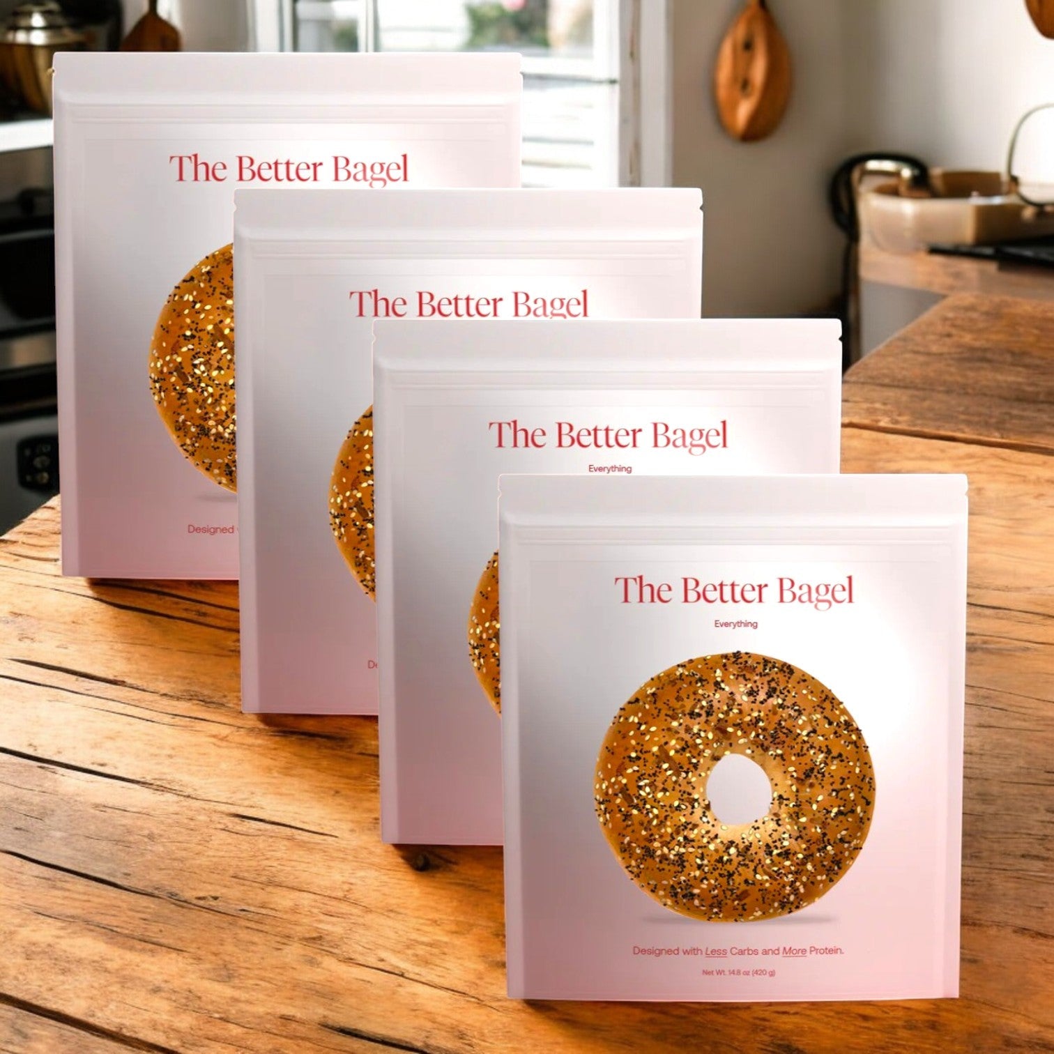 Four bags of "BetterBrand - The Everything Better Bagel" with a savory spice blend rest on a wooden kitchen table amidst a cozy background, highlighting the flavorful essence of 16 total bagels. In Stock-Ready to Ship!.