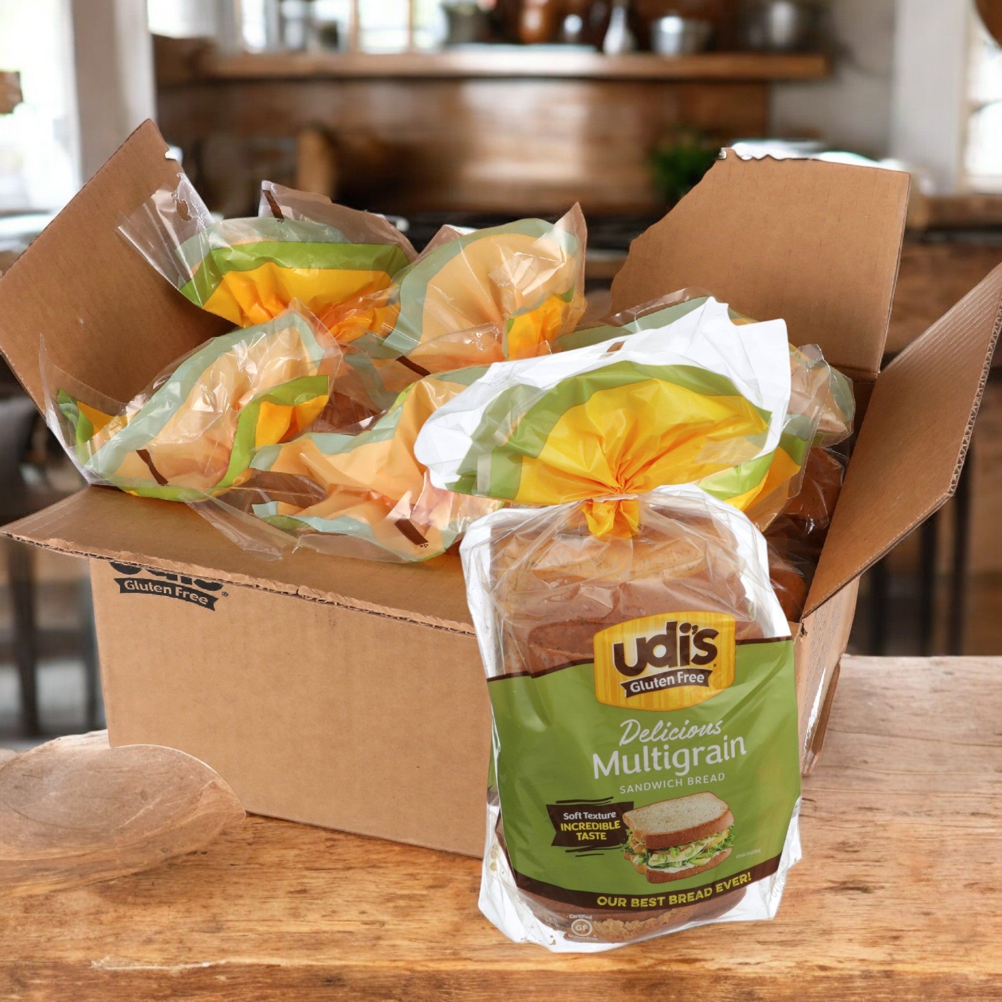 In a cozy kitchen, an open box of Udi's Bread Loaf Multigrain Gluten Free Sliced, 24 oz., 1 Case, 6 Count rests on a wooden table.