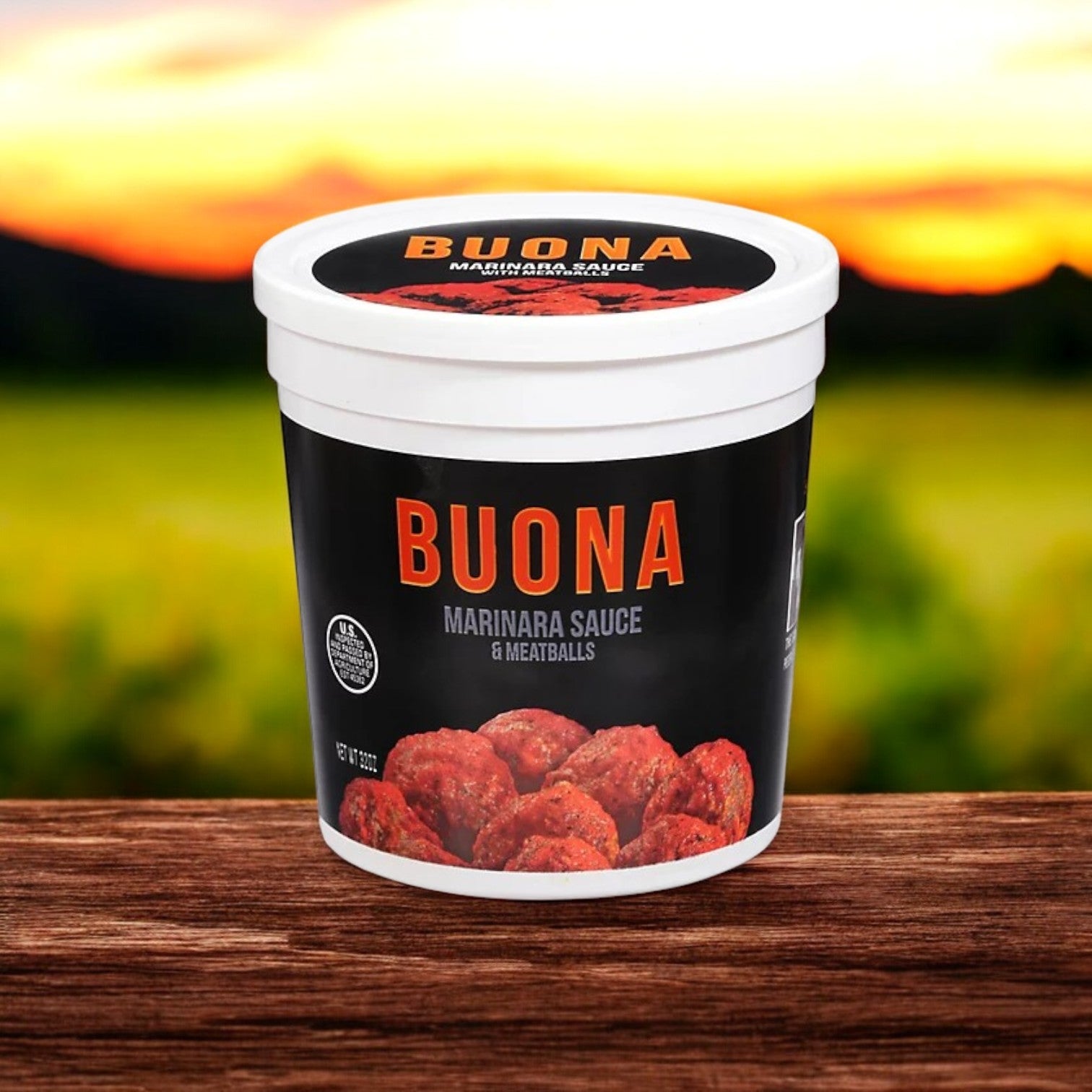 A 32 oz container of Buona Marinara Sauce & Meatballs sits on a wooden surface, capturing the essence of an Italian meal bundle, complemented by a rustic blurred outdoor background. Also available: Buona Gravy & Sliced Beef, Italian Style – 6 Pack.