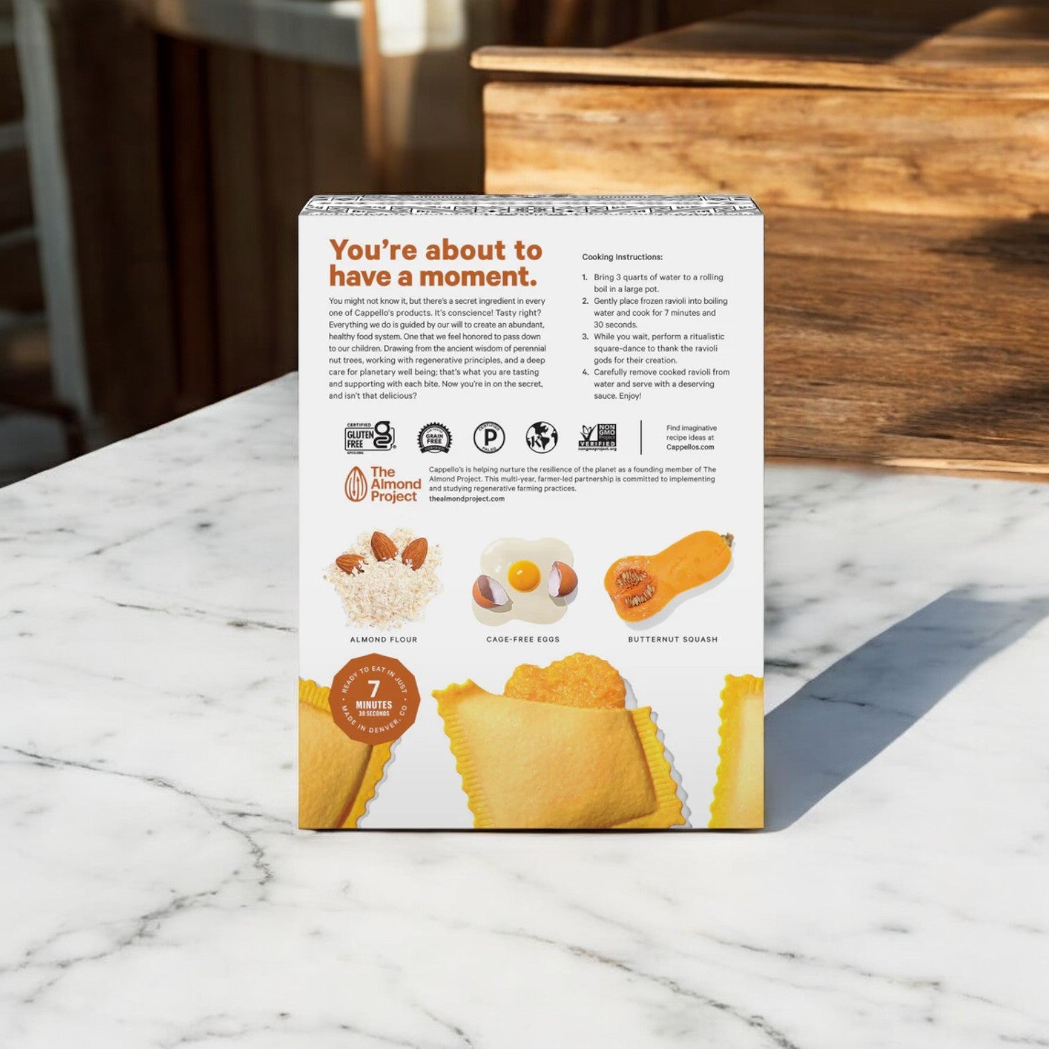 A box of Cappello's Butternut Squash Ravioli, made with almond flour and cage-free eggs, sits elegantly on a marble surface. This gluten-free pasta embodies Italian cooking at its finest and features detailed cooking instructions for a delightful meal.