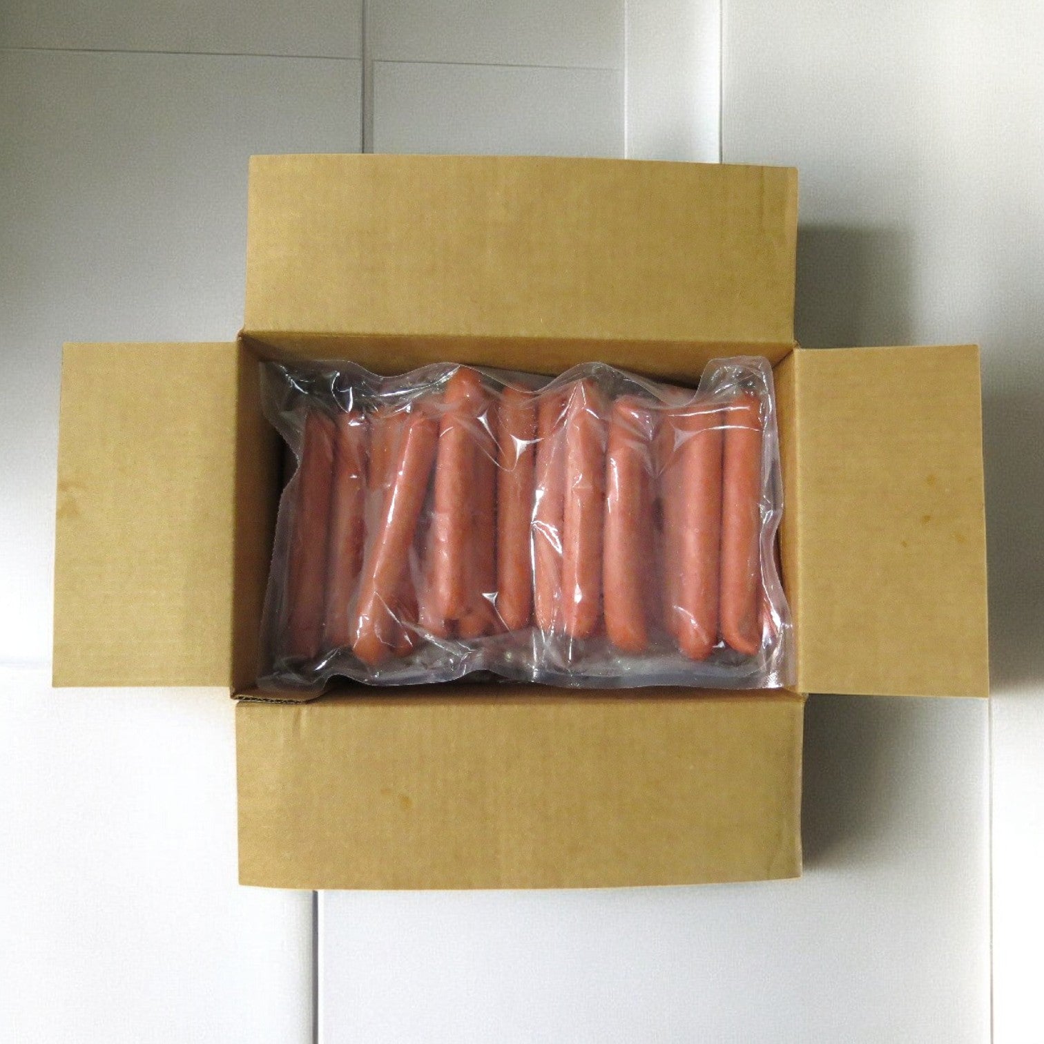A cardboard box of Vienna Beef's Vienna Frank All-Beef hot dogs, 10 lbs., with vacuum-sealed packages arranged in two rows on a white tiled surface.