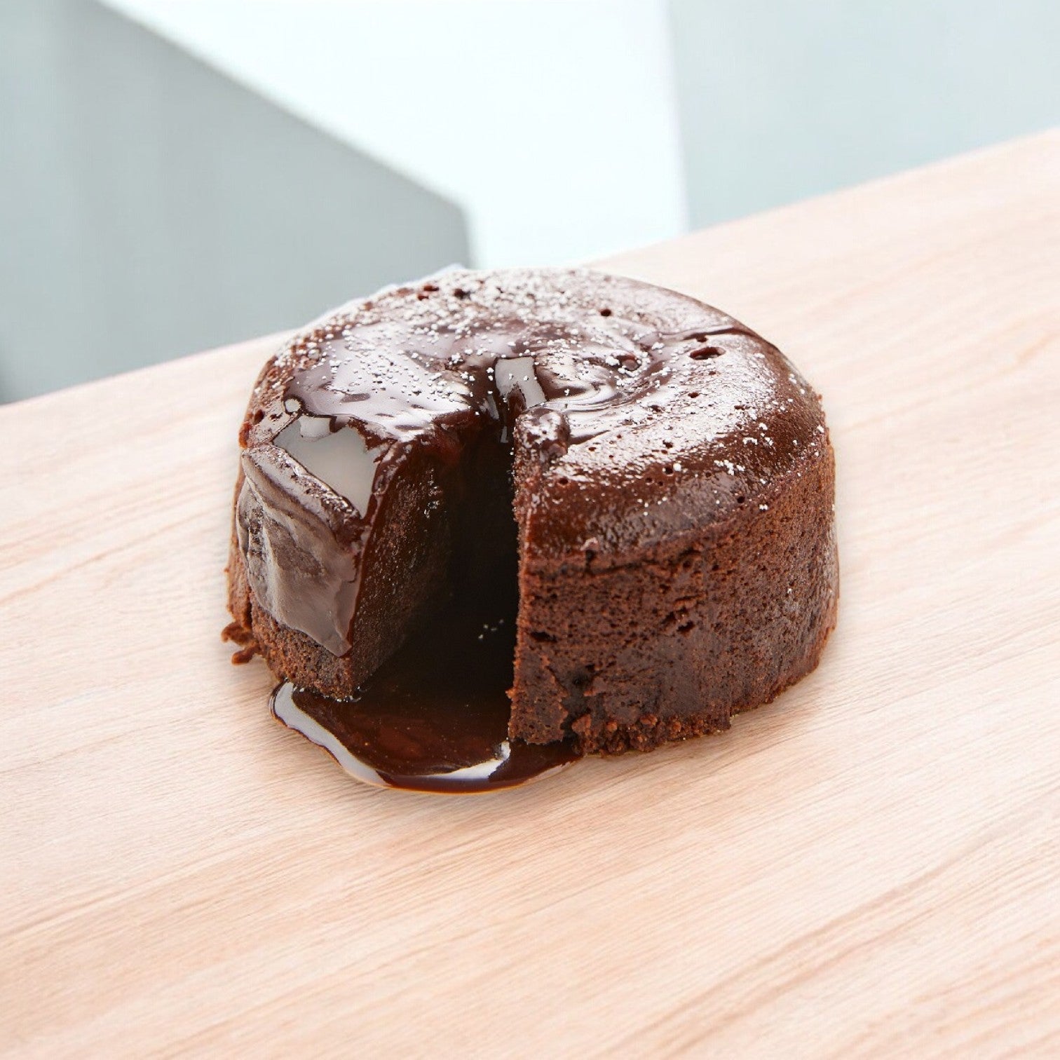 A Sysco Cake Fudge Divine Lava with a molten center is set on a light wooden surface.