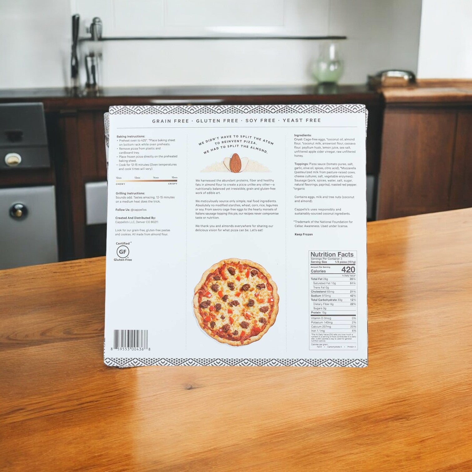 Back view of a Cappello's Italian Sausage with Roasted Red Peppers Pizza box (12 oz.), displaying ingredients, nutritional facts, and cooking instructions on a wooden table in a kitchen.