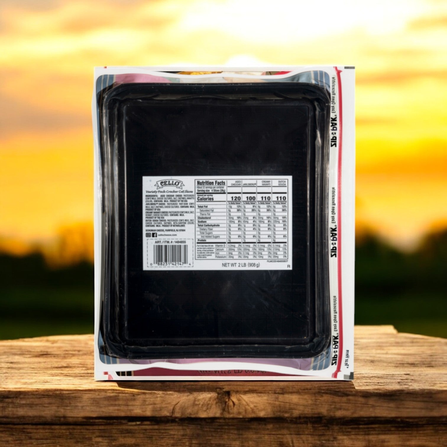 A plastic package of lasagna rests on a wooden surface with a sunset backdrop. Nearby, the Cello Variety Pack of Cracker Cut Premium Sliced Cheeses completes the scene, offering 2 lbs of gourmet delight while its nutrition facts label enhances your delicious choices.