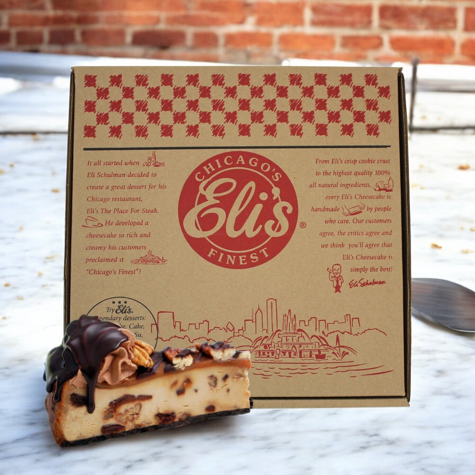 A slice of chocolate-topped Turtle Cheesecake sits elegantly in front of a Chicago's own Eli's Cheesecake box on a marble surface, highlighting the ultimate local dessert experience.