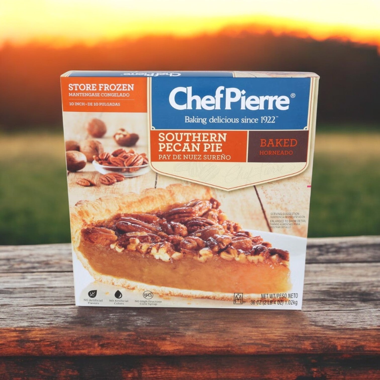 A 36 oz. Chef Pierre Pre-Baked Southern Pecan Pie rests elegantly on a wooden surface, its golden hues shining against a sunset backdrop. This pie promises the rich taste of authentic pecan filling, ready to savor with every decadent bite.