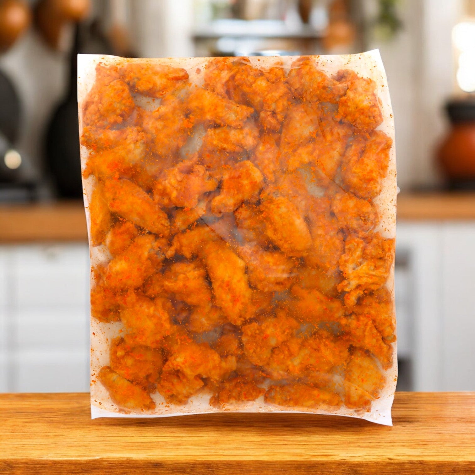 A package of Sysco Classic Chicken Wings Fire Cooked 1&2 Joints Small rests on the wooden counter in a cozy kitchen, ideal for a quick meal.